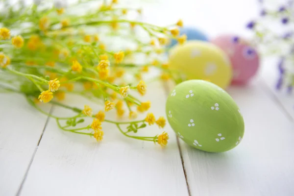 Oeufs de Pâques décorés colorés sur fond de bois blanc . — Photo