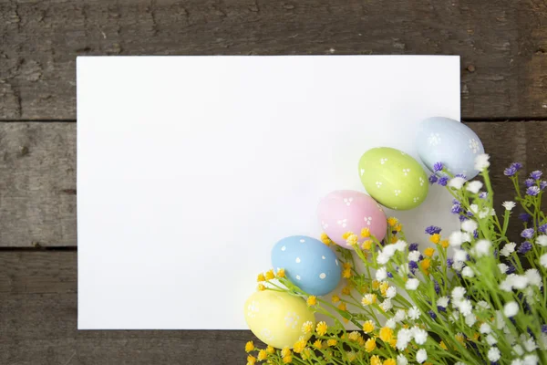 Easter greeting card with eggs and wildflowers over wood. — Stock Photo, Image