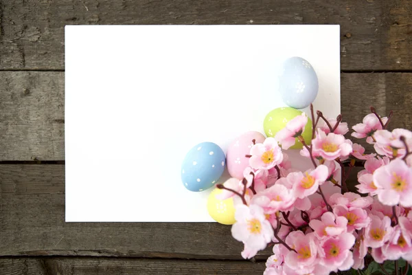 Easter eggs and blank note on wooden background — Stock Photo, Image