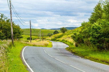 Yaz günü İskoçya, güneşli tepelerinde yol virajlı.
