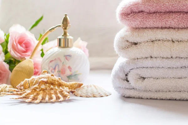 Arrangement de bain avec flacon de parfum, serviettes pliées et roses roses — Photo