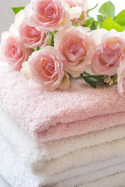 Serviettes pliées sur le comptoir de salle de bain avec des roses roses vives — Photo