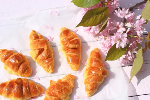 Färska franska croissanter på gamla trä bakgrund, romantisk frukost i trädgården — Stockfoto