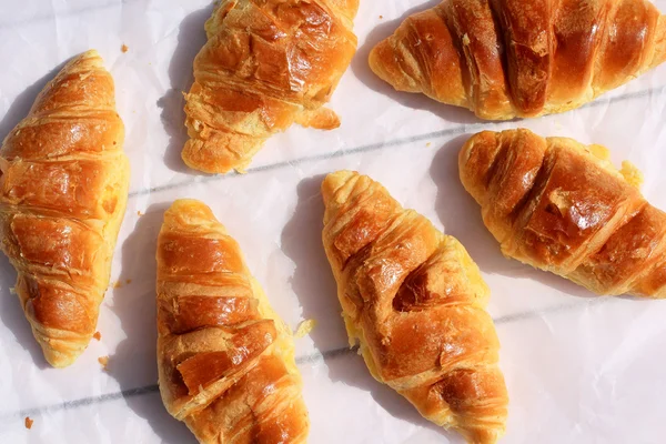 Verse croissants op oude houten achtergrond, plat — Stockfoto