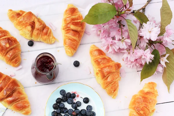 Färska franska croissanter på gamla trä bakgrund, romantisk frukost i trädgården — Stockfoto