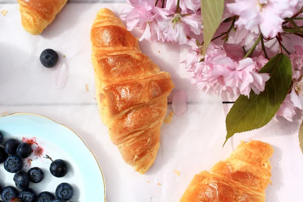 Färska franska croissanter på gamla trä bakgrund, romantisk frukost i trädgården — Stockfoto