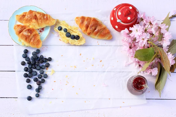 Färska franska croissanter på gamla trä bakgrund, romantisk frukost i trädgården med kopia utrymme — Stockfoto