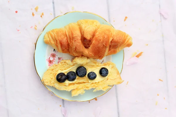 Färska croissanter på gamla trä bakgrund med färskt smör och blåbär — Stockfoto