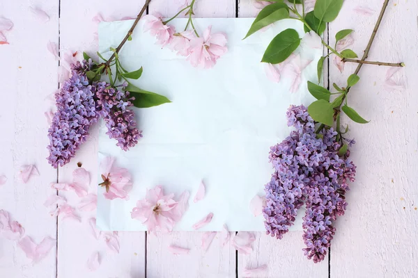 Schöner, frühlingshafter romantischer Hintergrund mit weißem Papier, Flieder und Kirschblüten — Stockfoto