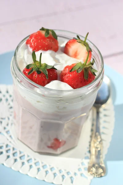 Frische Erdbeeren mit Fruchtjoghurt und Schlagsahne auf hellrosa Holztisch — Stockfoto