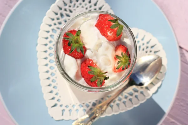 Fresas frescas con yogur de frutas y crema batida sobre una mesa de madera rosa claro —  Fotos de Stock