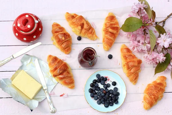 Leckeres Frühstück mit frischen Croissants und reifen Beeren auf altem Holzhintergrund, selektiver Fokus — Stockfoto