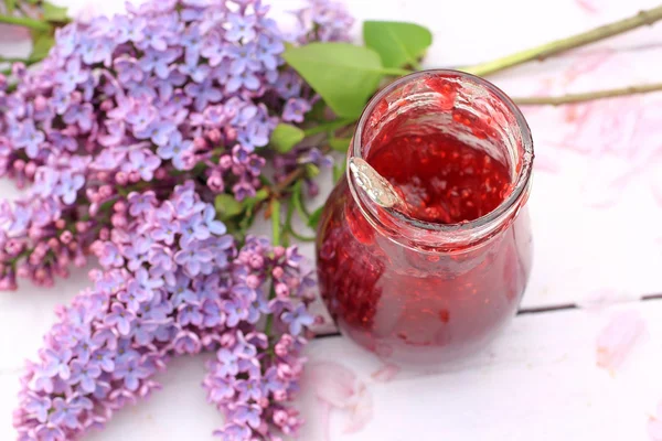 Ein Glas frische Himbeermarmelade auf hellem rustikalem Hintergrund, Nahaufnahme, im Garten, selektiver Fokus — Stockfoto