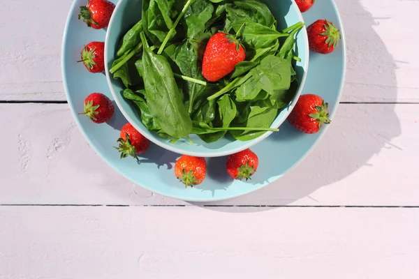 Fresh spinach salad with spinach and strawberries on wooden light pink table — Stock Photo, Image