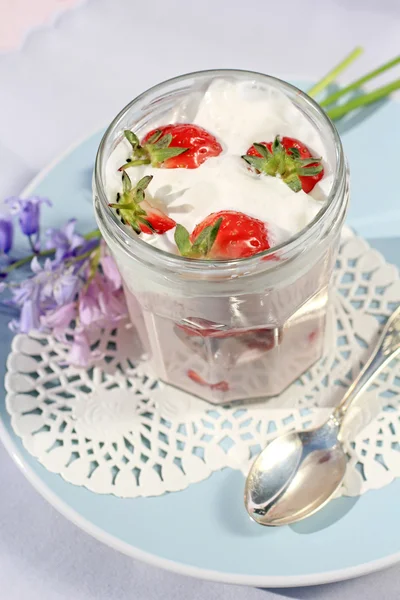 Fresas frescas con yogur de frutas y crema batida sobre una mesa de madera rosa claro —  Fotos de Stock
