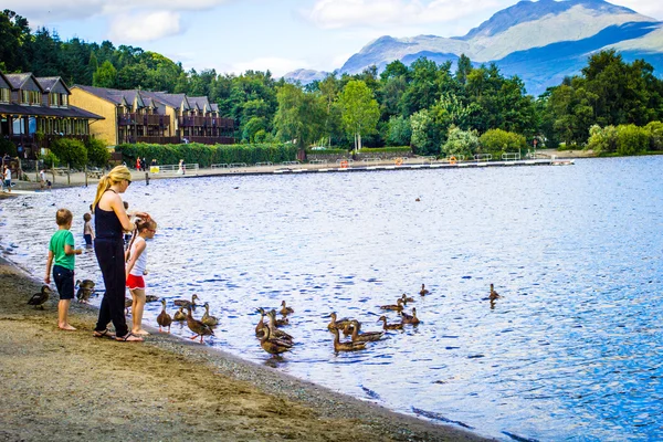 Ludzie bawią się w słoneczny dzień nad jeziorem Loch Lomond w Luss Szkocja, 21 lipca, 2016 — Zdjęcie stockowe