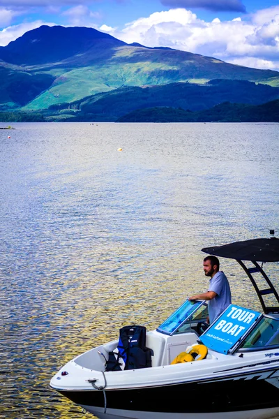 2016 年 7 月 21 日、スコットランドのロッホ ローモンド湖でのツアーのモーター ボートの男 — ストック写真