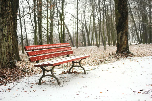 Banco vermelho no parque coberto de neve no inverno — Fotografia de Stock