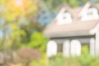 Evin arka planı bulanık. Ev binasının önündeki ağaçlar ve bahçe, doğadaki modern ev, yeşil çevre kavramlı soyut mimari