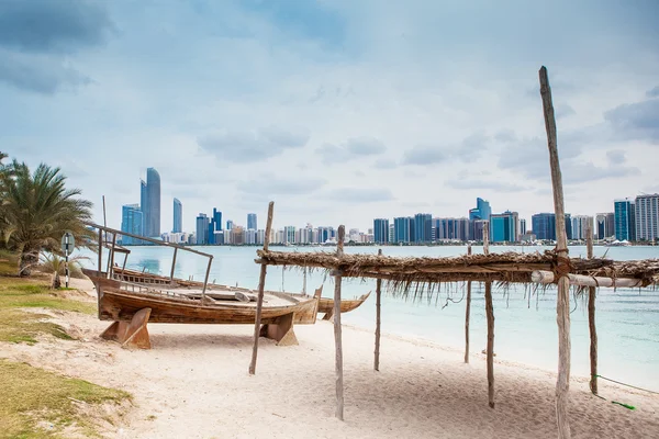 Playa de mar con boath de madera vieja y rascacielos de lujo — Foto de Stock