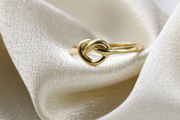 Anello d'oro nella forma di cuore su una seta beige — Foto Stock