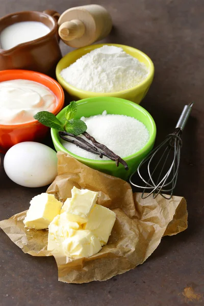 Ingredientes para repostería: mantequilla, leche, huevos, harina y azúcar de vainilla sobre un fondo de madera — Foto de Stock
