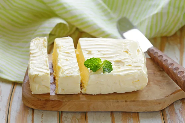 Blok van verse biologische boter op een houten bord — Stockfoto