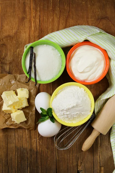 Ingredientes para repostería: mantequilla, leche, huevos, harina y azúcar de vainilla sobre un fondo de madera — Foto de Stock