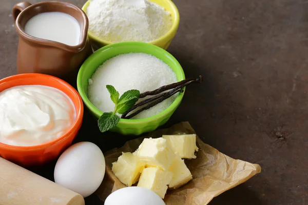 Ingrediënten voor gebak - boter, melk, eieren, bloem en vanille suiker op een houten achtergrond — Stockfoto