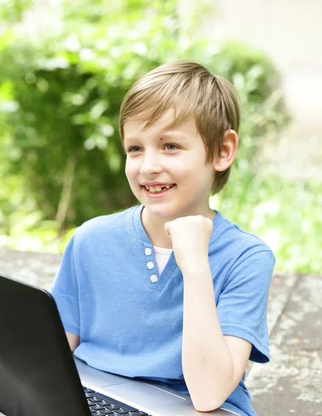 Boy playing on the computer (laptop) in a park Stock Image