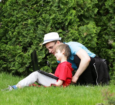 Baba ve oğul bilgisayar (laptop) bir parkta oynamak