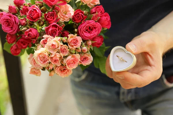 Hombre con un ramo de rosas y un anillo de diamantes, listo para hacer una propuesta —  Fotos de Stock