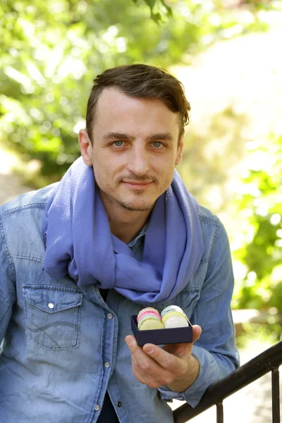Красивый молодой человек с коробкой французских макарон — стоковое фото