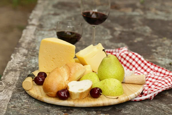 Cheeseboard with pears and wine on a table in the garden — Stock Photo, Image