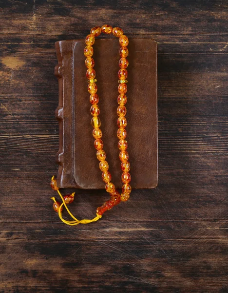 Book in a vintage leather bound, and amber beads — Stock Photo, Image