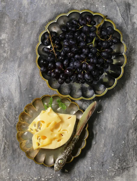 Cheese and fresh black grapes on vintage silver plates — Stock Photo, Image
