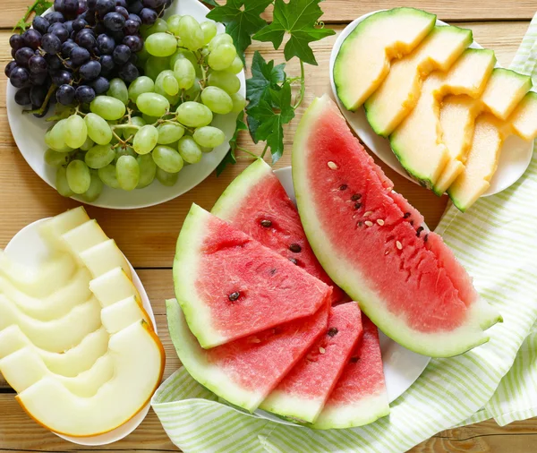 olgun organik meyve karpuz, karpuz kavun ve üzüm ahşap bir masa, üstten görünüm