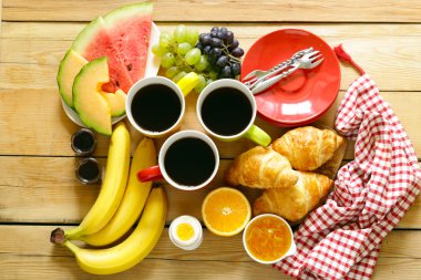 kahve, kruvasan ve meyve kahvaltı ahşap bir tabloda, üstten görünüm