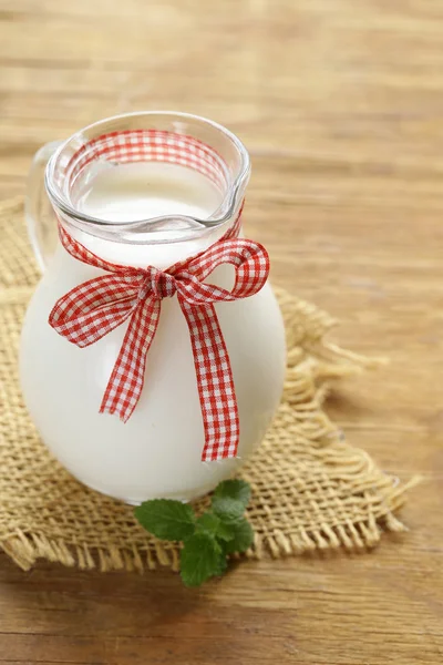 Latte biologico naturale in un barattolo di vetro su un tavolo di legno — Foto Stock