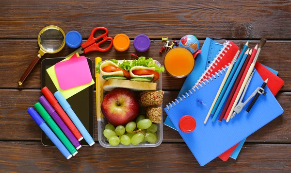 School stationery and lunch box with apple, grapes and sandwich — Stock Photo, Image