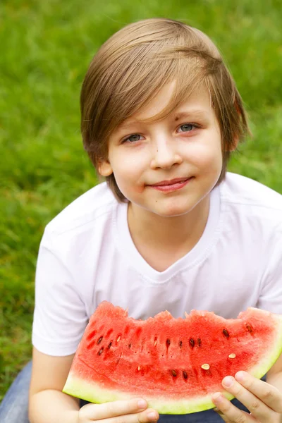 sevimli sarışın çocuk yeşil çayır on kırmızı bir karpuz yiyor
