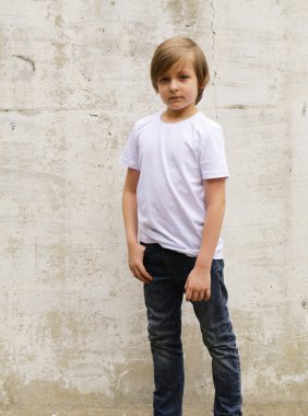 sevimli sarışın çocuk kot ve beyaz bir gömlek duvar arka plan üzerinde poz