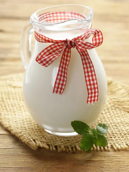 Naturalne ekologiczne mleko w szklanym słoju na drewnianym stole — Zdjęcie stockowe