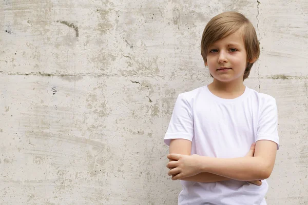 청바지와 흰 셔츠 벽 배경에 포즈에 귀여운 금발 소년 — 스톡 사진