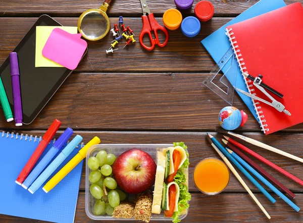Школьные принадлежности и обеденная коробка с яблоком, виноградом и сэндвичем — стоковое фото