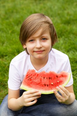 sevimli sarışın çocuk yeşil çayır on kırmızı bir karpuz yiyor