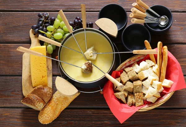 Conjunto tradicional de utensílios para fondue, com pão, queijo e uvas — Fotografia de Stock