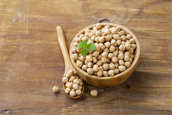 Raw chickpeas in a wooden bowl on the table — Stock Photo, Image