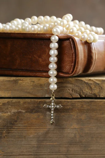 Old book (bible) and the Christian symbol cross on pearl necklace — Stock Photo, Image