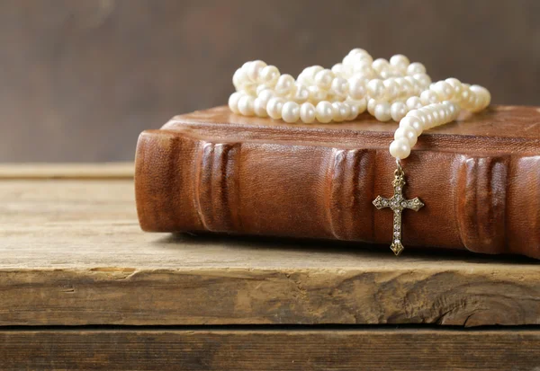 Old book (bible) and the Christian symbol cross on pearl necklace — Stock Photo, Image